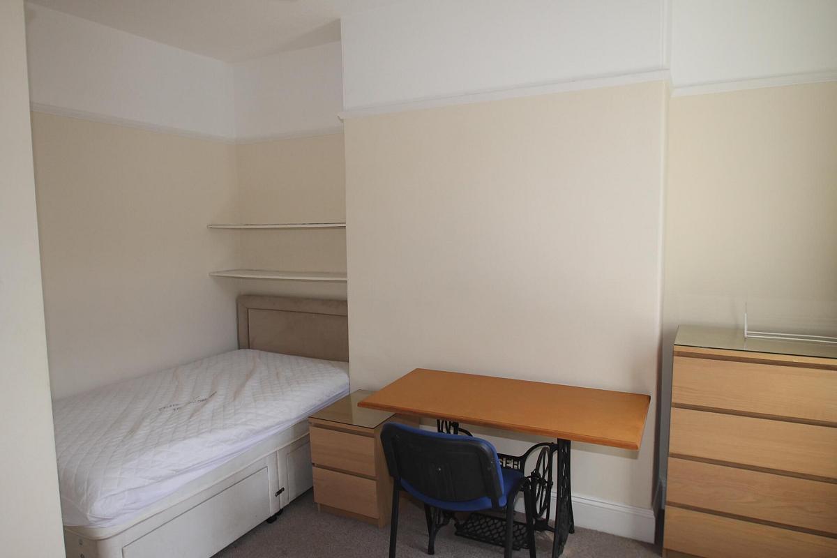 fourth student bedroom with double bed, two shelves above bed, bedside table, desk with blue chair, chest of drawers, two door wardrobe