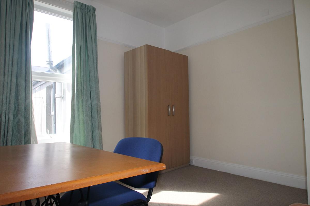 fourth student bedroom with double bed, two door wardrobe, and desk with blue chair