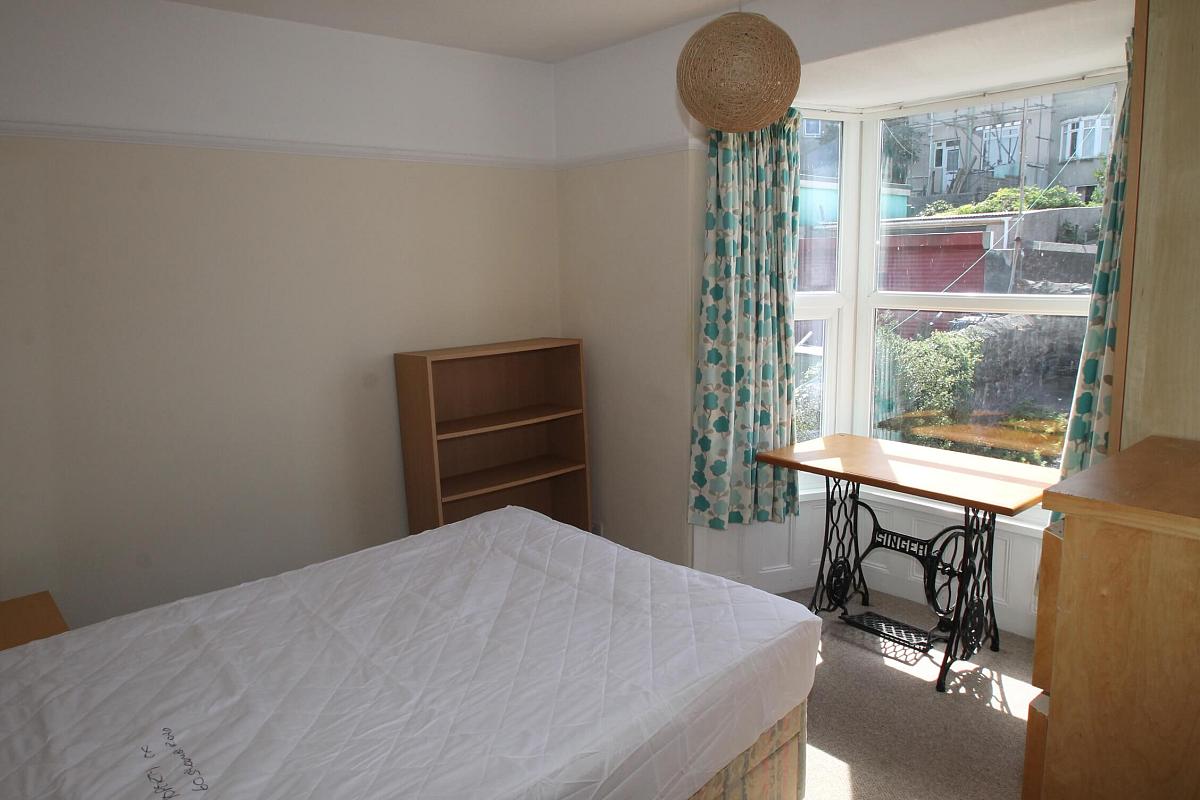 third student bedroom with double bed, shelving unit, chest of drawers, bedside table, desk in front of window