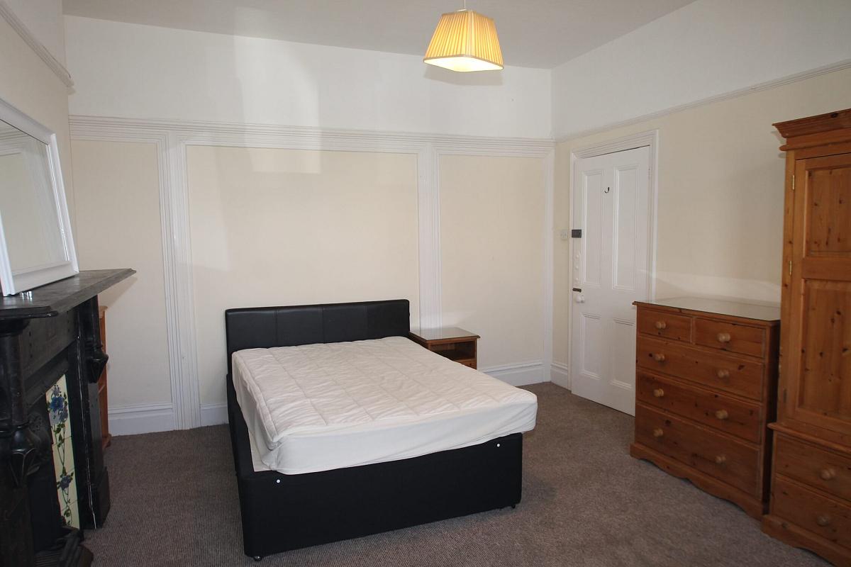 first student bedroom with double bed, chest of drawers, two door wardrobe, bedside table, desk in front of large bay window