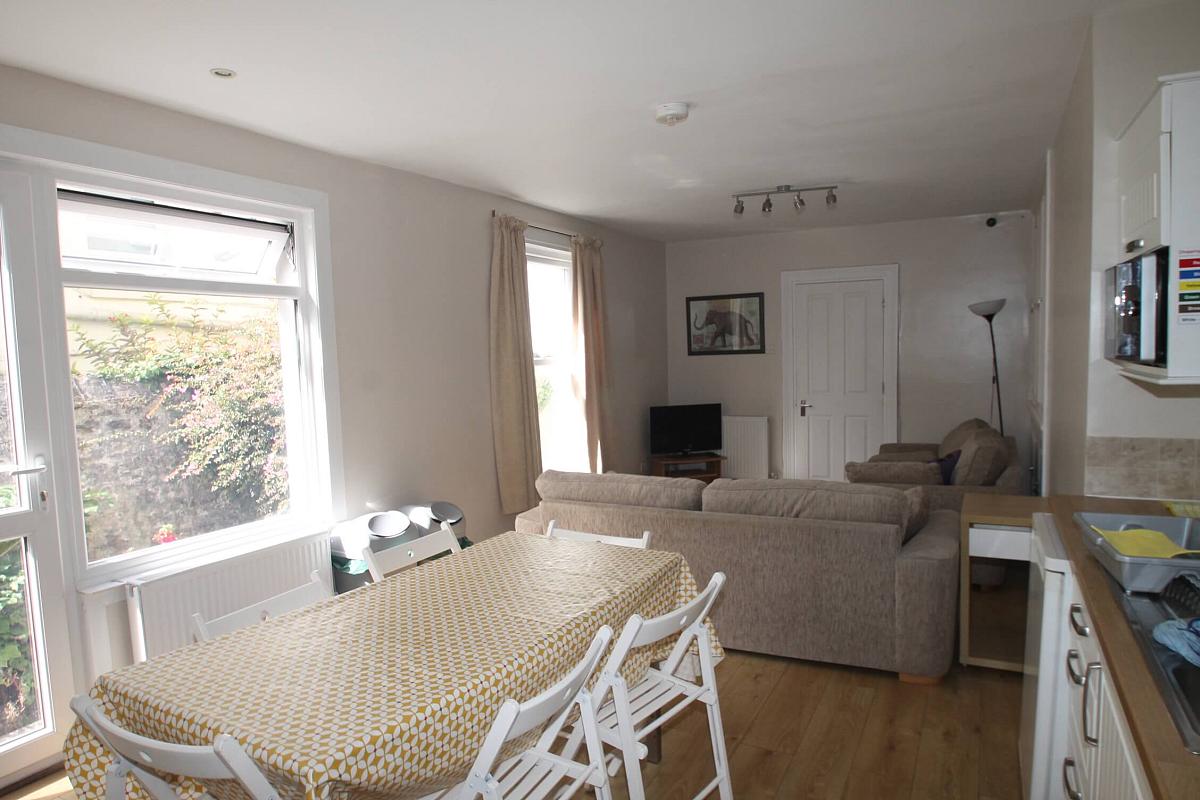 kitchen and living area with large dining table with six dining chairs, two two-seater sofas and tv on tv stand
