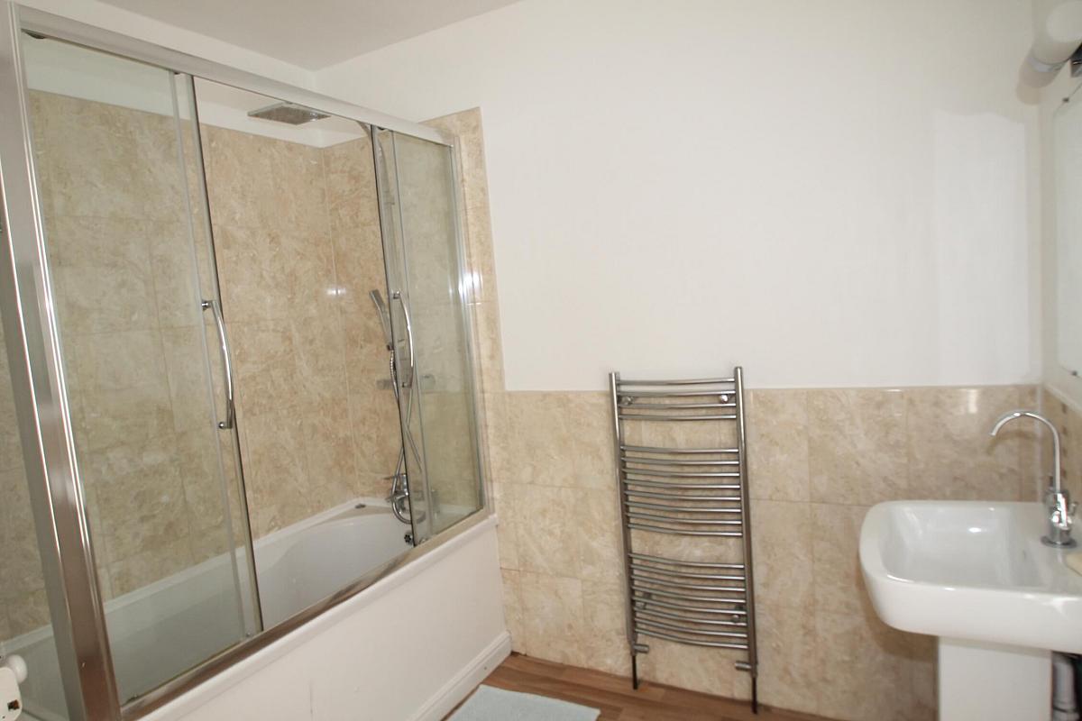 Large shared bathroom with enclosed bath with shower head, towel rack radiator and mirror mounted above sink