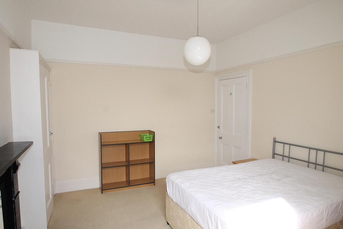 Fourth student bedroom with double bed, bedside table, shelving unit, two built-in wardrobes and black feature fireplace