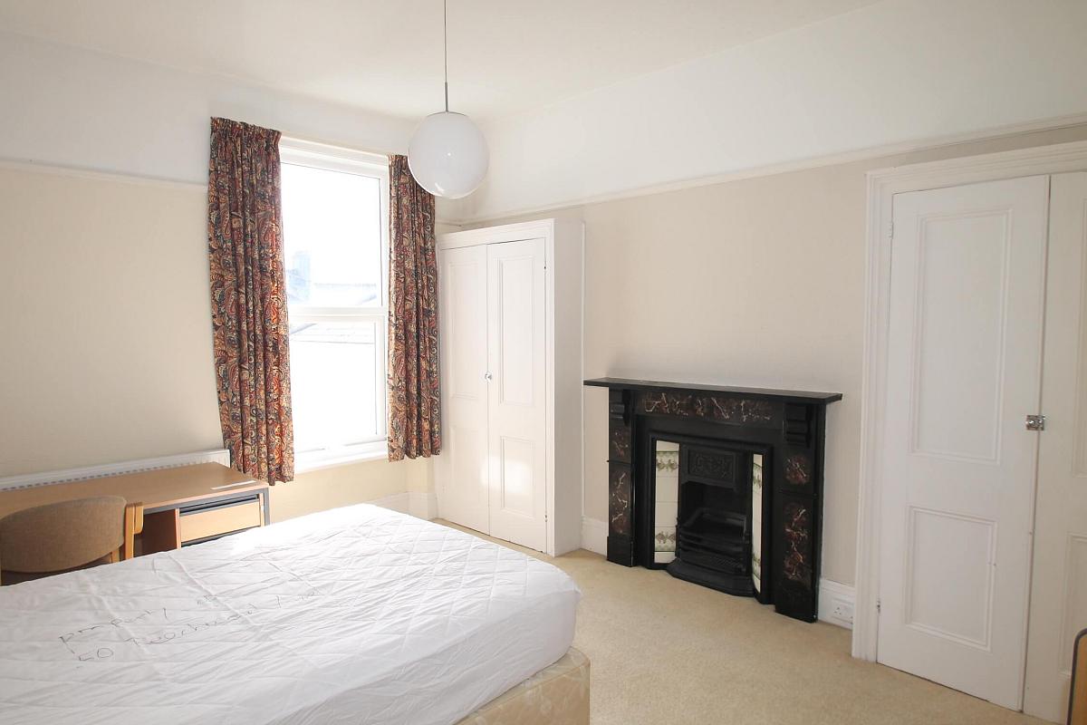 Fourth student bedroom with double bed, desk with chair, two built-in wardrobes and black feature fireplace