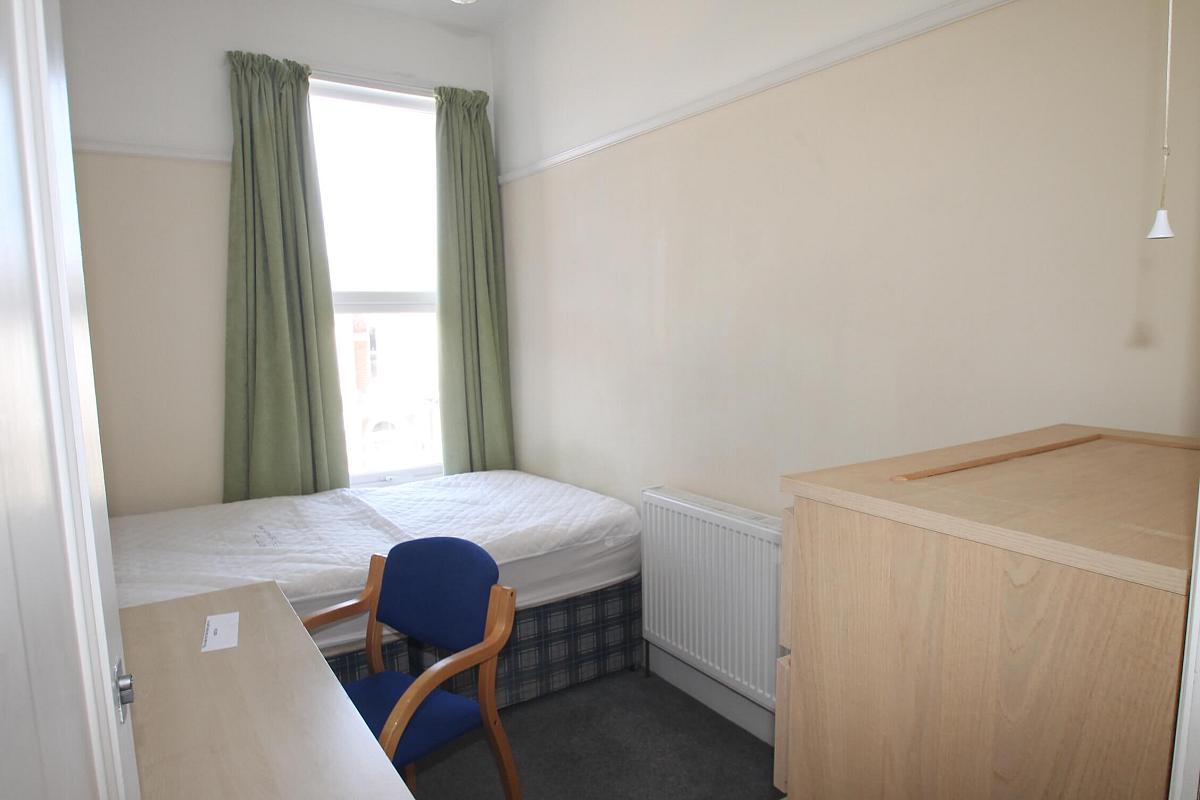 Sixth student bedroom with double bed, chest of drawers and desk with blue chair