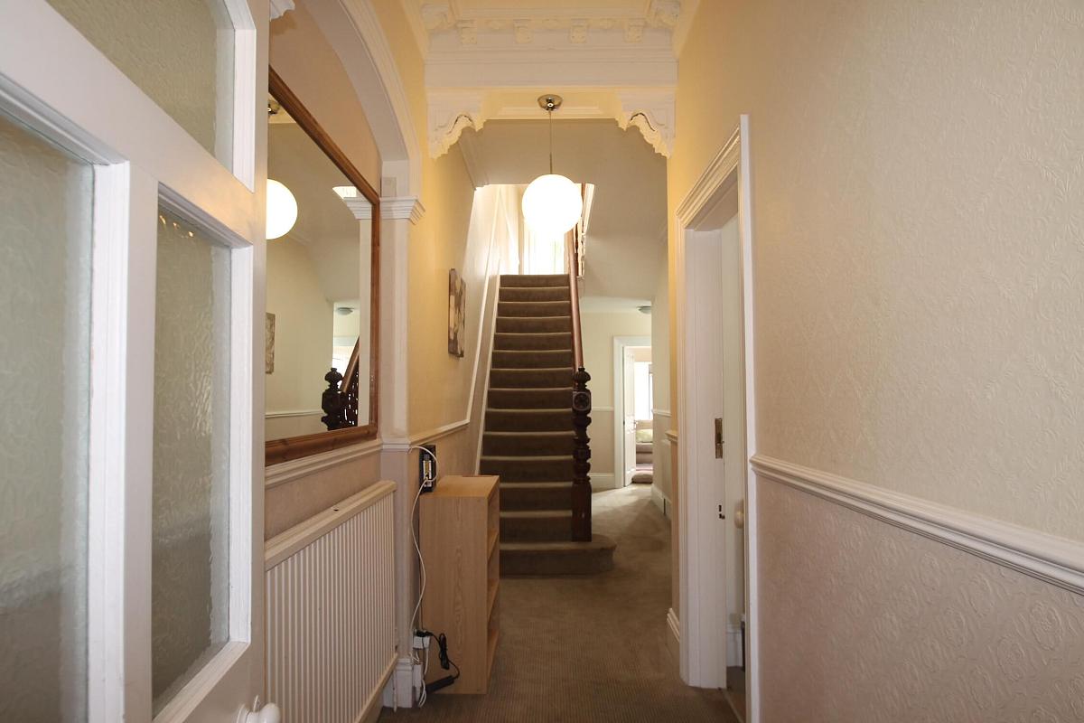 Hallway from the front door, large mirror mounted on the wall and staircase to first floor