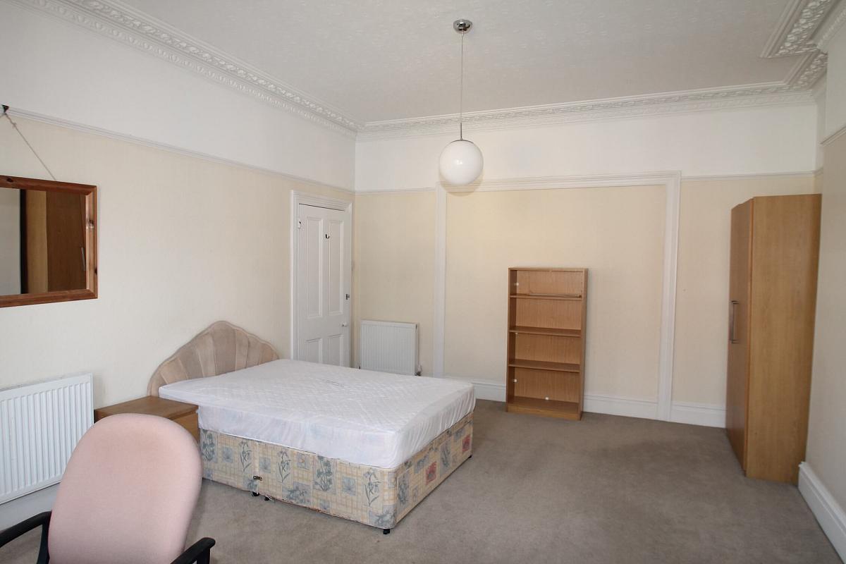 First student bedroom with double bed, two door wardrobe, shelving unit, bedside table, desk with office chair and wall mounted mirror