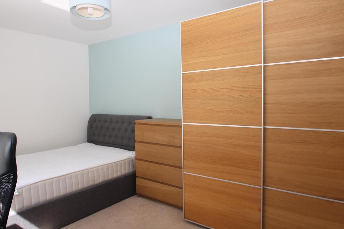 third student bedroom with double bed, chest of drawers, two door wardrobe and desk with black office chair