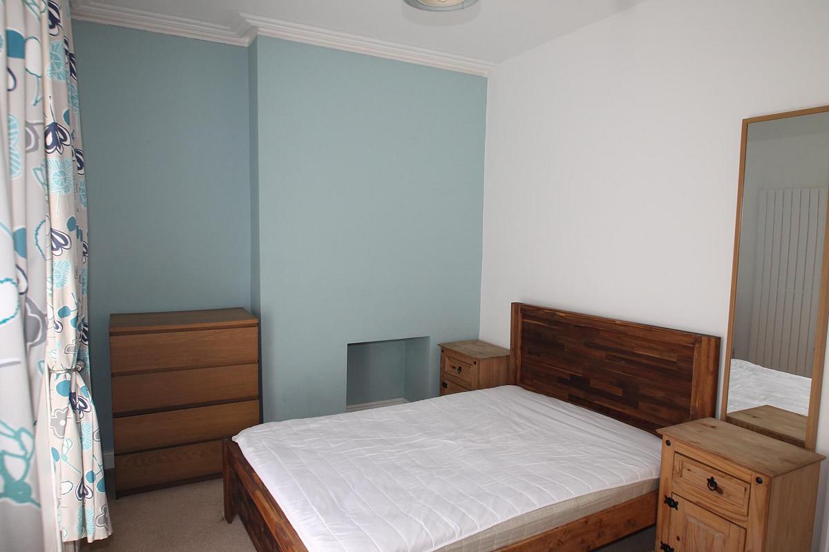 first student room with double bed, two bedside tables, chest of drawers and full length mirror