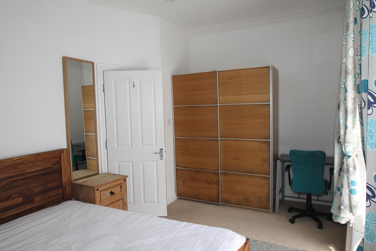 first student room with double bed, large two door wardrobe, full length mirror, bedside table and desk with blue office chair