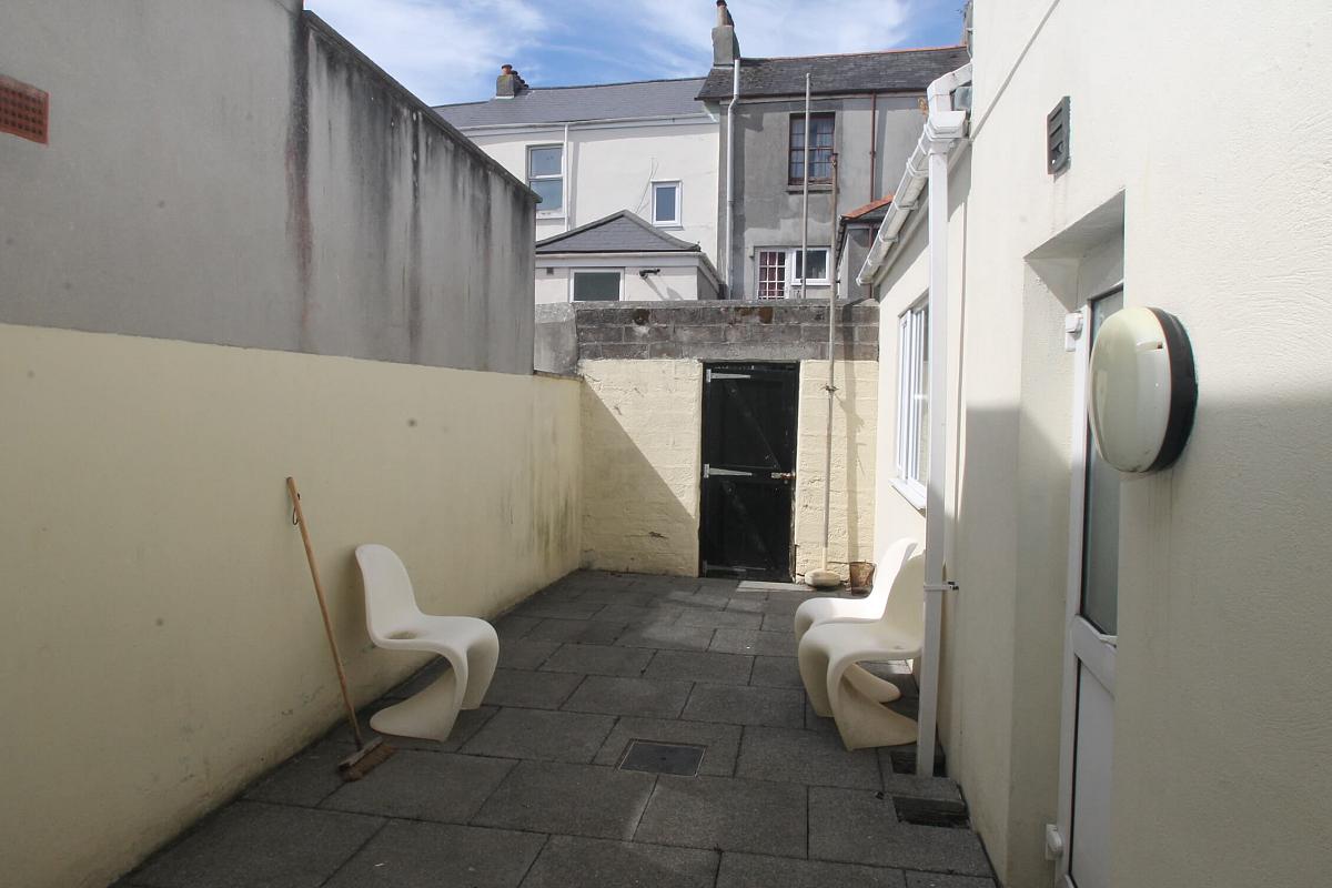 back patio of property with outdoor furniture and back gate leading to back alley