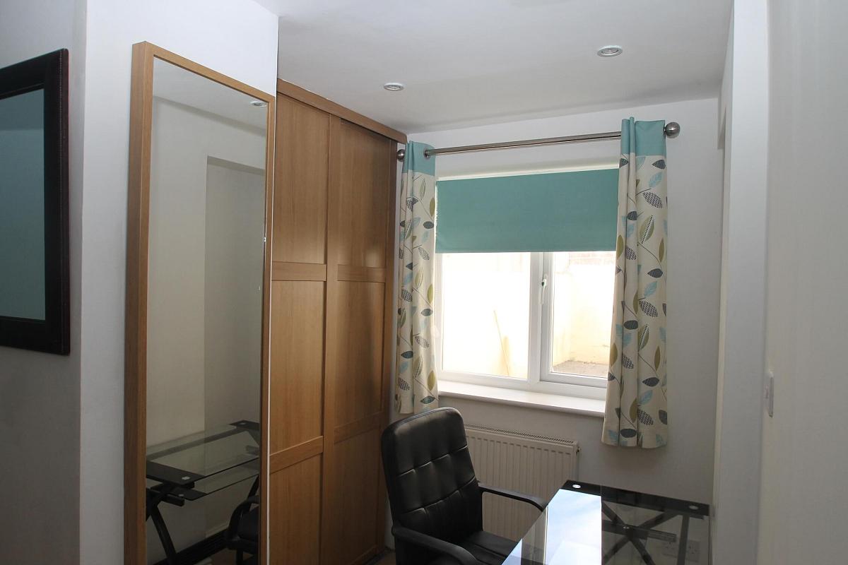 second student bedroom with full length mirror, glass desk with office chair and two door wardrobe