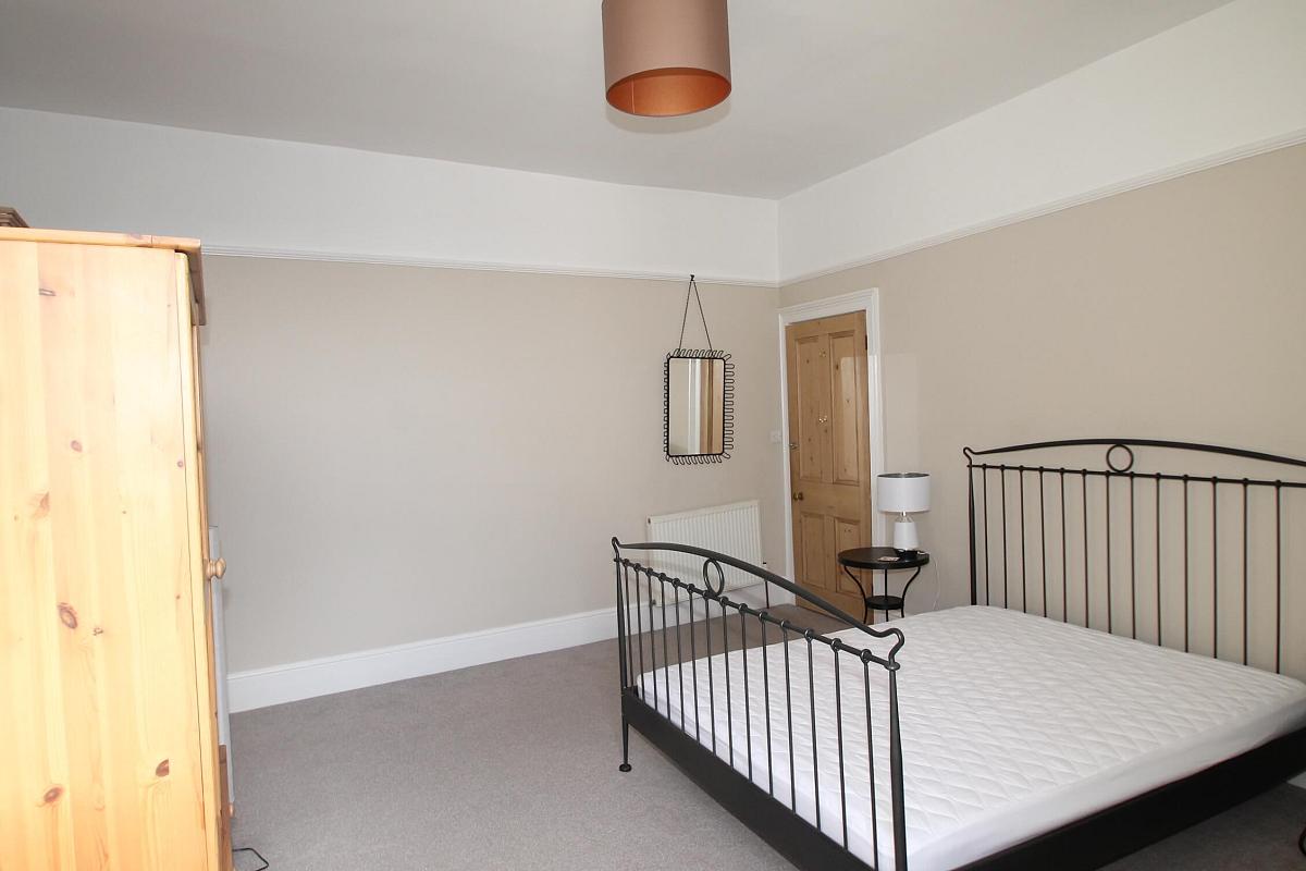 fourth student room with double bed, two door wardrobe and mirror hung on wall