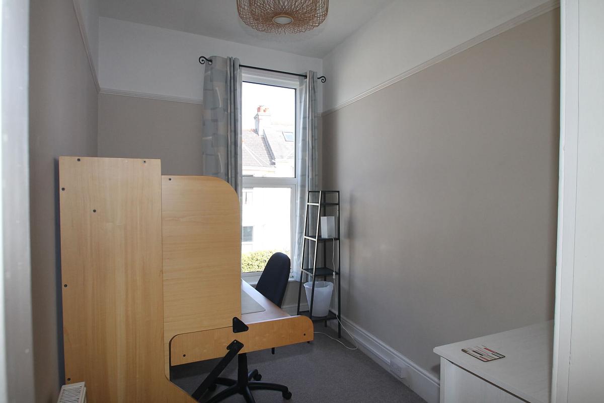 Office room with desk and office chair, chest of drawers and shelving unit
