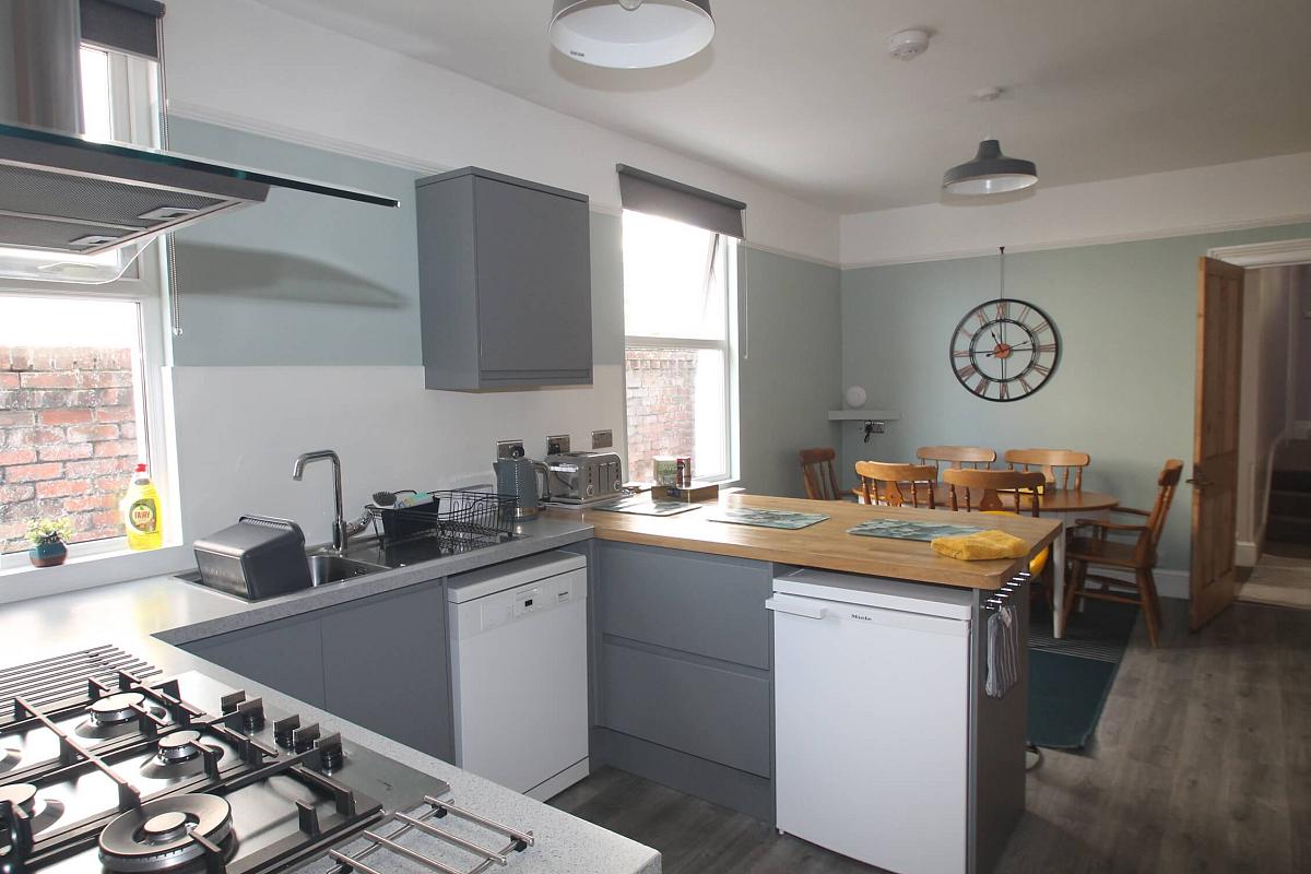 kitchen and dining area with dishwasher, small fridge, gas hob and cooker and dining table with six dining chairs