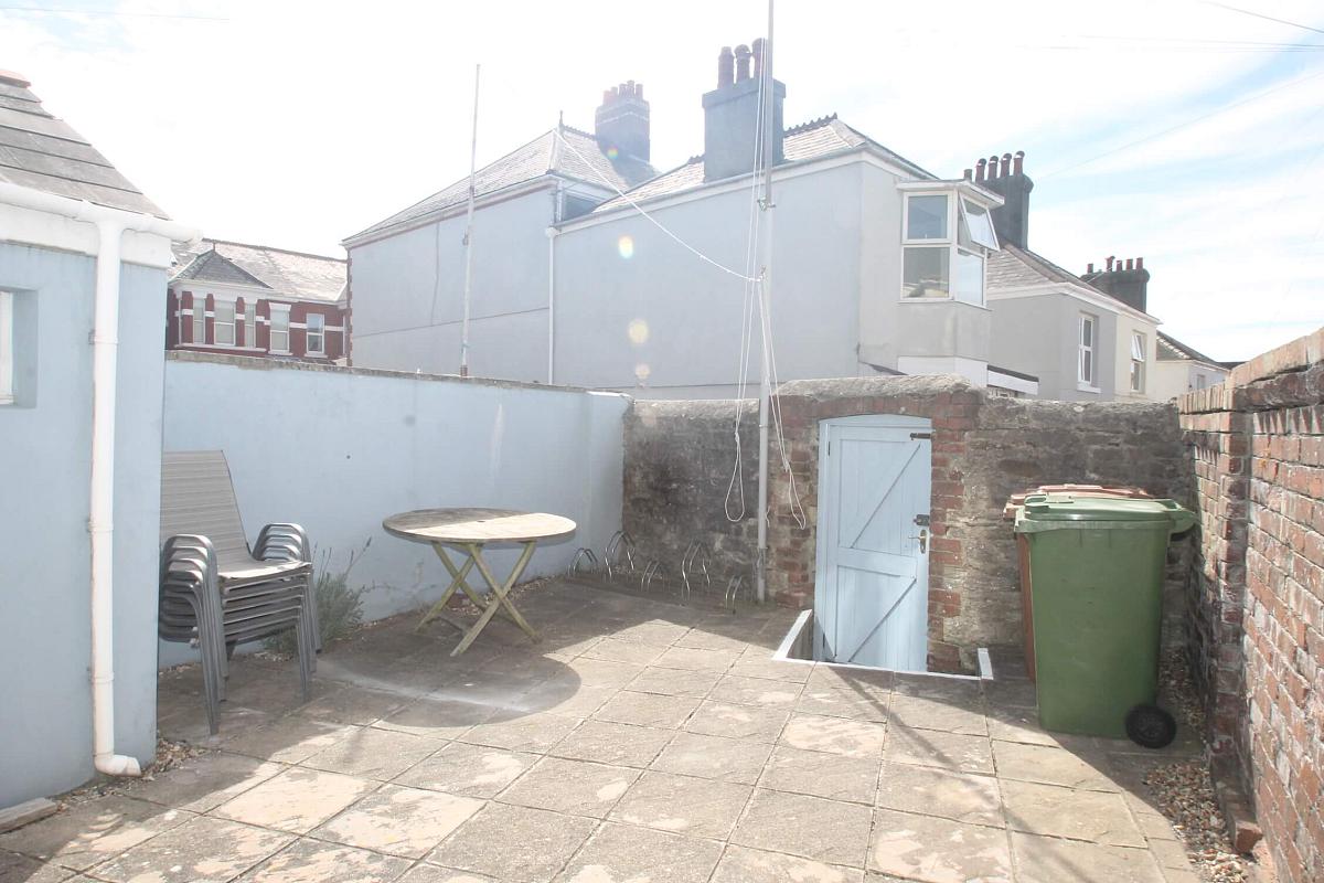 Back garden of property with outside furniture and back gate