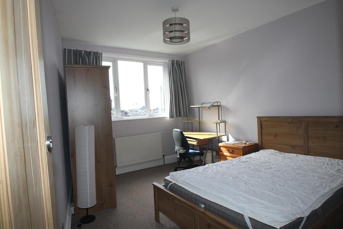 second student room with double bed, three door wardrobe, bedside table and desk with blue office chair