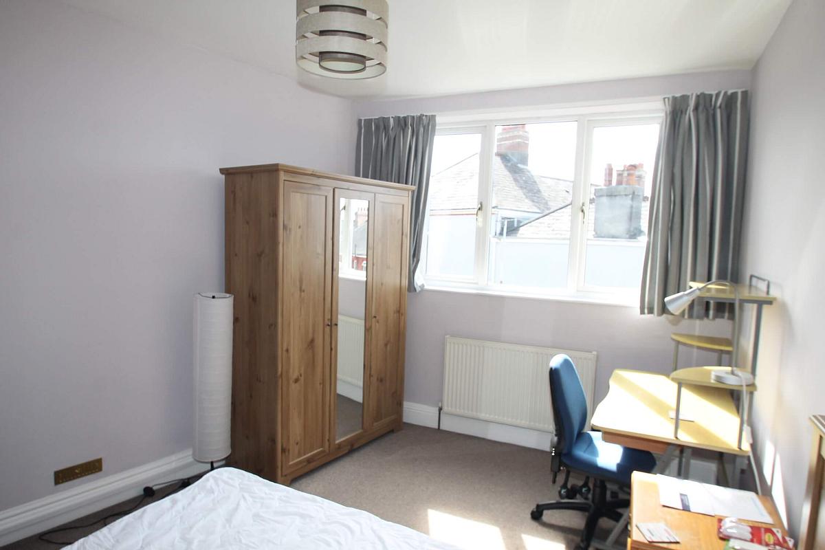 second student bedroom with double bed, three door wardrobe with full length mirror door, tall corner lamp and desk with blue office chair