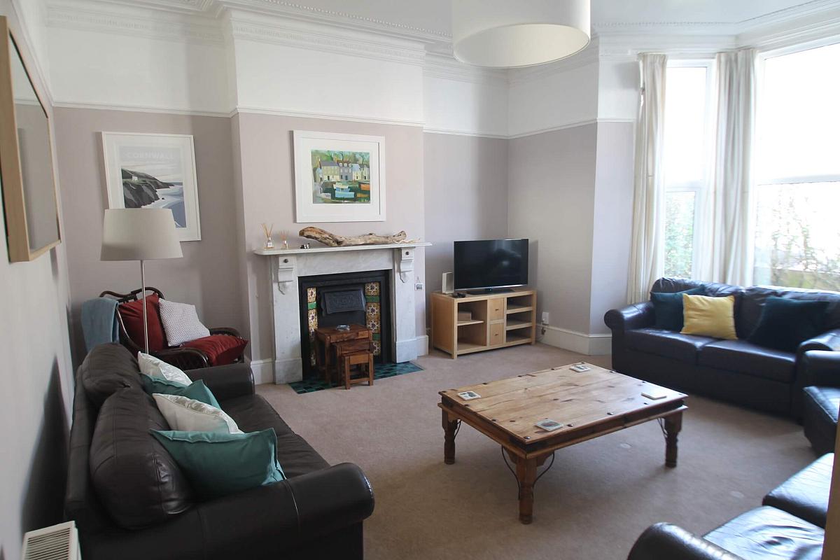 shared living room with three leather two-seater sofas, two armchairs, coffee table, fireplace and tv on tv stands