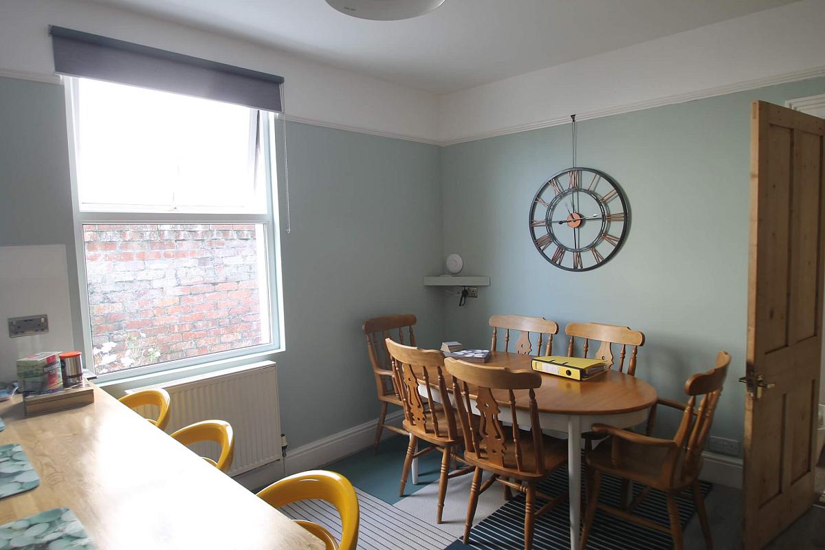 open kitchen and dining area with breakfast bar with three yellow barstools and dining table with six dining chairs