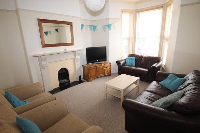 shared living room with two leather two-seater sofas, two armchairs, coffee table and television on tv stand