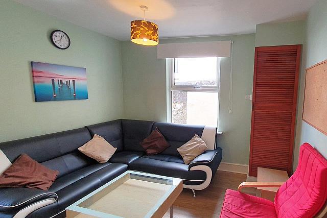 Shared living room with L shaped sofa and red single arm chair