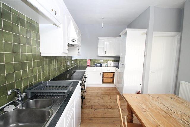Green tiled shared kitchen with fridge freezer, cooker and hob, sink and dining table