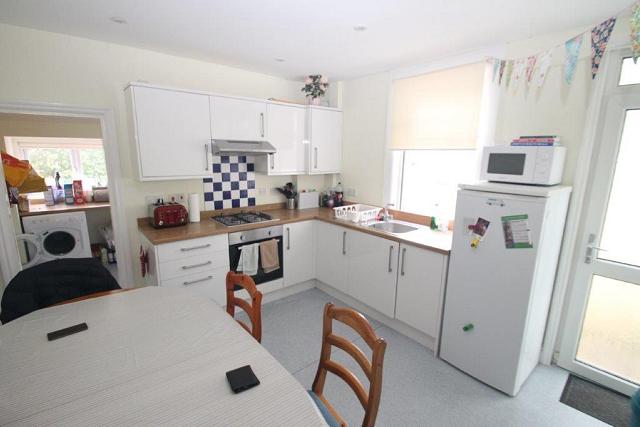 Shared kitchen with cooker, hob and fridge. Leading into utility room